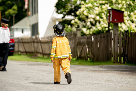 Young child dressed as firefighter for Halloween, representing childhood dreams of future careers, role play, imagination, community helpers, fire prevention, fire safety, and costume celebration.
