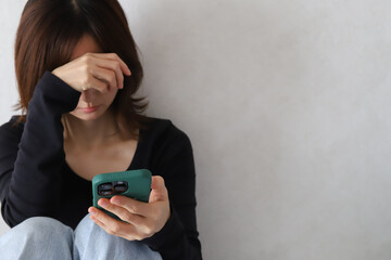 スマホを見て落ち込む女性