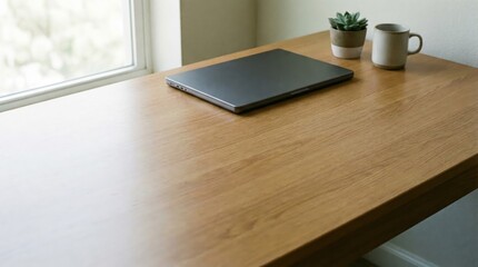 Naklejka premium Minimalist workspace setup with closed laptop succulent plant and coffee mug on wooden desk