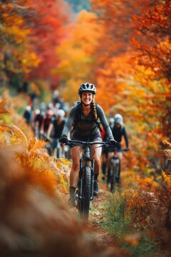 Cardio sports cycling biking exercise training, healthy lifestyle. A woman mountain biking through a forest in the fall. She is wearing a helmet, gloves, and boots.
