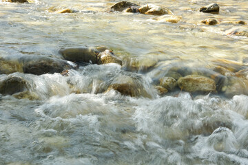 Fototapeta premium Abstract Water Background in Motion, River Stones Under Clear Flow
