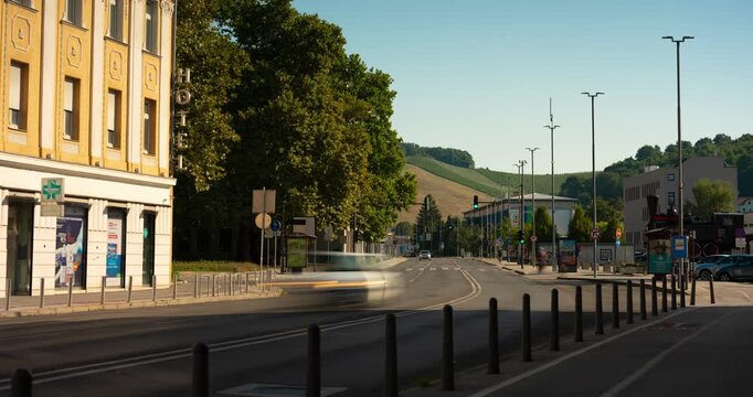 Maribor, Slovenia - August 10, 2025: Timelapse. City Street View in Maribor, Slovenia, Featuring Historic Hotel Building, Main Road with Motion Blur, and Green Hills in the Background
