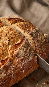 fresh sourdough bread being sliced with a knife on a rustic linen cloth surface