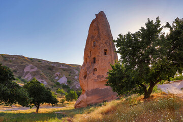 A photograph from the world-famous Cappadocia tourist region. The photograph shows Uçhisar Castle and the fairy chimneys surrounding it. Summer.