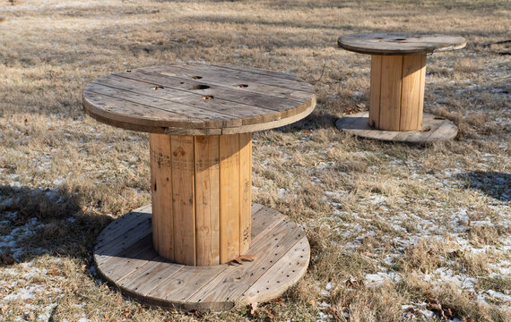 Side view of a large wooden cable spool or timber reel on a grassy field for power distribution and industrial utility infrastructure themes