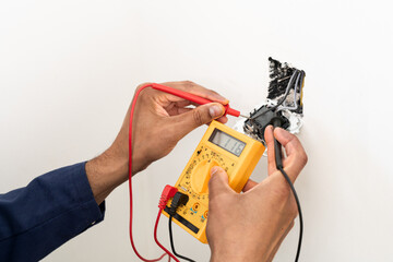 Close-up on an hands of electrician fixing an electrical outlet and measuring the voltage at a...