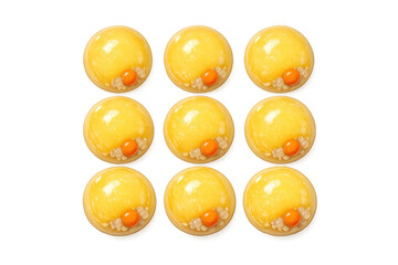 Fototapeta premium Nine golden yellow spherical desserts with orange centers and white pearls arranged in a grid