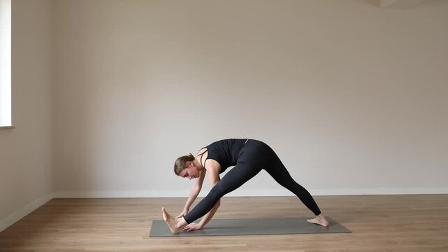 A young woman practicing yoga in a bright modern studio, focusing on balance, breathing, and mindfulness.