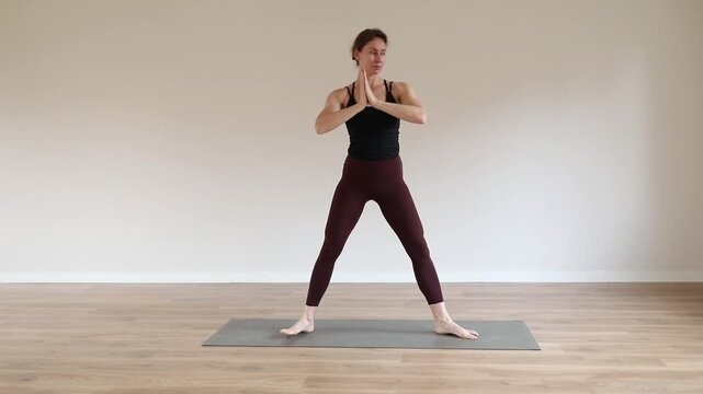 A young woman practicing yoga in a bright modern studio, focusing on balance, breathing, and mindfulness.