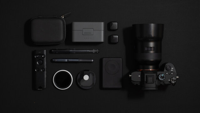 Flat Lay of Black Camera Gear and Tech Gadgets on Black Background （黒背景に配置された黒いカメラ機材とガジェットのフラットレイ）