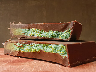 Pieces of Dubai chocolate bars with pistachios and knafeh on wooden table, closeup