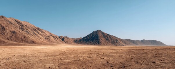 Naklejka premium Vast arid desert plain with rugged mountain ridges under clear blue sky offering wide copy space for climate change concepts environmental awareness and minimalist background design