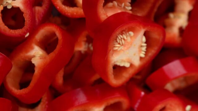 Freshly cut rings of red Capia pepper rotate smoothly, showcasing their thin, crunchy walls and vibrant red color. Perfect for cooking and salad content.