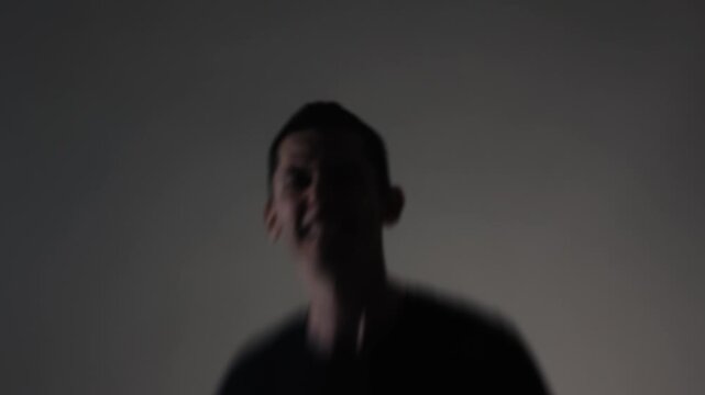 A young male rock vocalist screams aggressively into the camera, his face contorted with destructive emotion. Motion blur emphasizes unstable emotional intensity.