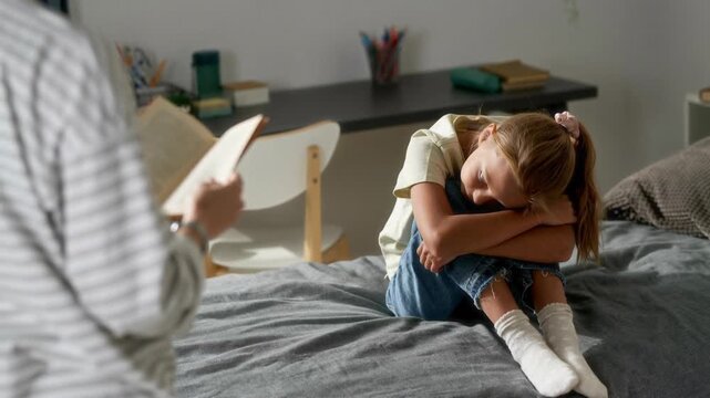 Frustrated girl child hugging knees on bed listening to mother reminding kid about completing homework in bedroom, AI generated video