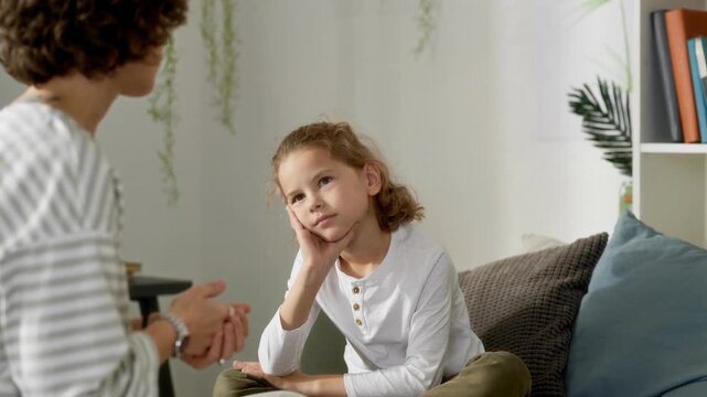 Bored preteen boy child listening to mother while having serious conversation with parent sitting together on bed, AI generated footage