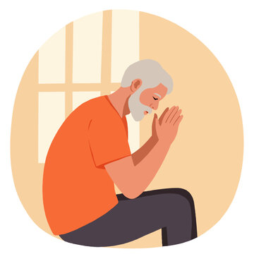 Elderly man sitting with hands clasped in prayer indoors  