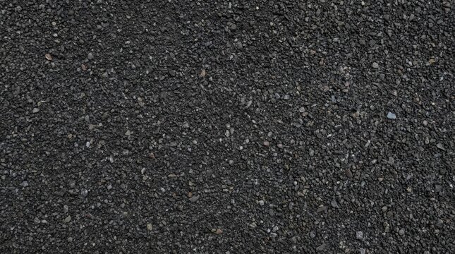 Close-up of a dark grey asphalt road texture, featuring small pebbles and gravel. Ideal for industrial, urban, and construction backgrounds.