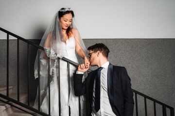 Groom kissing bride's hand on wedding day stairs © Jelena