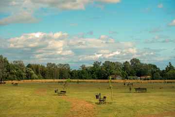 Scenice view of a village park with benches and forest background © Bogdan