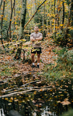 Obraz premium A man stands in a forest with his arms crossed