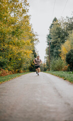 A man runs down a road in the woods