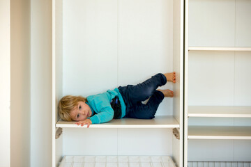 Cute child, sit in a white box in open wardrope