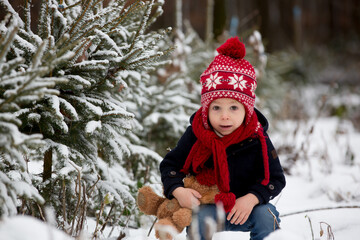Cute toddler child in the park, standing between christmas trees