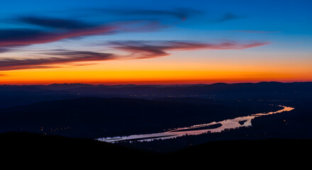 Scenic view of a vibrant sunset casting warm hues over a winding river and distant hills