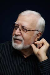 Obraz premium Older man smiles while thinking about memories in a dark room during a quiet evening