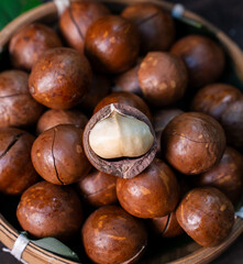 Obraz premium Close up macadamia nuts in bamboo basket with cracked shell