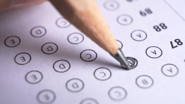 Close-up of a pencil tip shading multiple choice circles on a standardized test answer sheet during an exam
