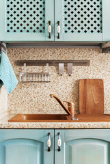 Kitchen sink area with cabinets and clean countertop