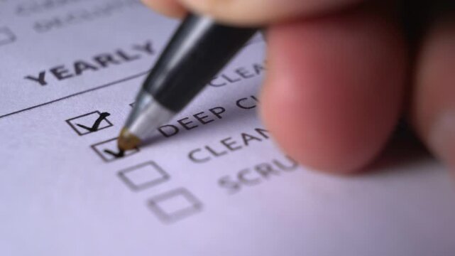 Close-up perspective of a person's hand ticking multiple empty square checkboxes on a paper form using a pen