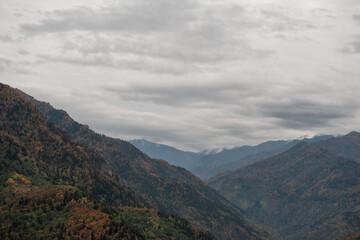Fototapeta premium Autumn mountains stretch across dramatic valley under clouds