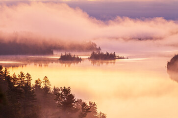 Fototapeta premium Islands in early morning fog on a Boundary Waters lake in northern Minnesota during autumn