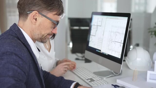Architecture and engineering team collaborating on project blueprints using computer aided design software in an office. Business and architecture concept