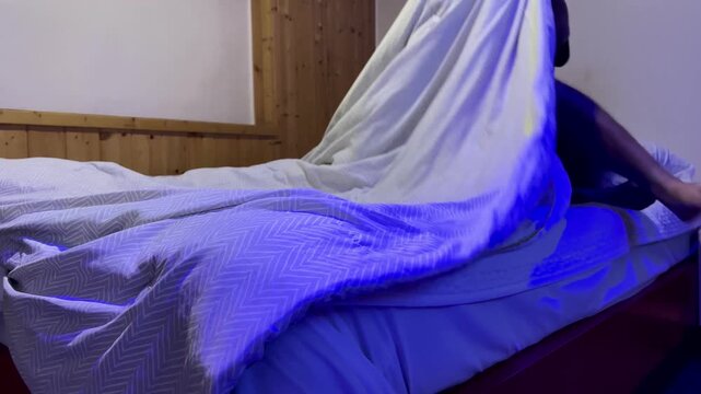 Man Getting into Bed and Covering with Blanket Before Sleep