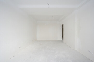 Fototapeta premium spacious, empty room with white walls and floor, minimalist design, one radiator, recessed ceiling lights, a doorway leading to another space, no furniture, clean and bright.