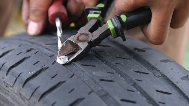 Hand removing a nail from a flat tire