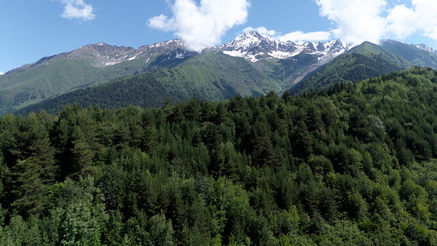 Aerial drone landscape of Mount Ushba, one of the most iconic peaks of the Caucasus Mountains, overlooking the green valleys and alpine villages near Mestia in the Svaneti region of Georgia. Snow-capp