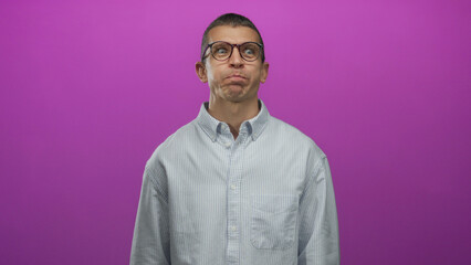 Man with glasses makes a funny face against a vibrant pink background wearing a striped shirt showcasing a playful and quirky expression