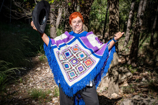 Mujer pelirroja en el bosque con un poncho echo a mano de ganchillo