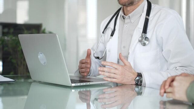 Doctor man consulting patient using laptop, discussing medical information during healthcare examination in modern clinic. Medicine, healthcare and science concept