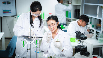 Fototapeta premium Scientists collaborating on plant biotechnology research in laboratory, highlighting teamwork, sustainability, clean energy, and climate action for ESG, green innovation, and corporate communication