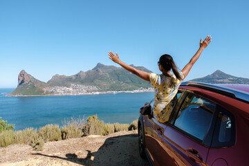 Chapman's Peak Drive on the Cape Peninsula near Cape Town in South Africa on a bright and sunny afternoon. Cape Town, a woman with hands up on a road trip,a woman happy in a rental car © Fokke Baarssen