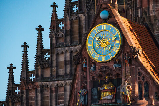 View of the ornate facade of the Frauenkirche, with gold figures and an astronomical clock against a clear sky, Nuremberg, Germany.