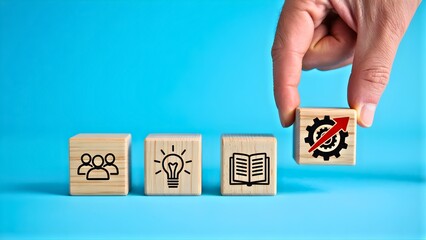 Wooden blocks symbolizing business growth and success with icons representing teamwork, ideas, learning, and progress displayed against a blue background