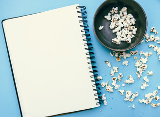 Blank notebook mockup with popcorn on blue backdrop.