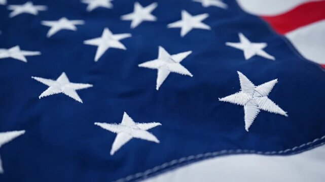 Macro view of white embroidered stars on rippling blue American flag fabric creating a patriotic texture background